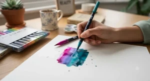 Hand holding a colourful brush pen at a 45-degree angle against a dot-grid journal paper during a lettering session.